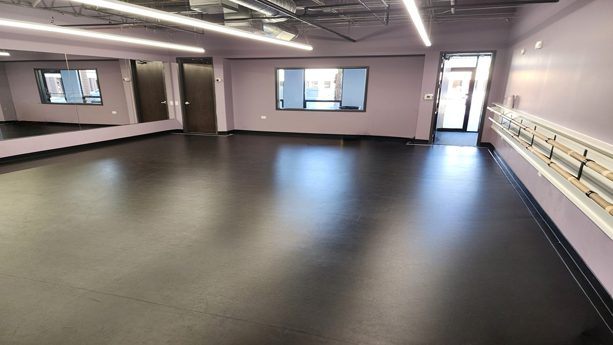Interior of Expression Dance Studio in Westmont, Illinois, featuring a spacious dance room with black sprung flooring, ballet barres, and mirrored wall.